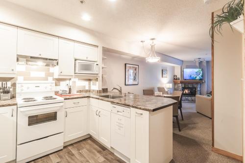 a kitchen with white appliances and a living room at Lake Placid Lodge by Elevate Vacations in Whistler