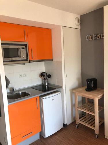une petite cuisine avec des armoires orange et un évier dans l'établissement Studio - Centre Ville - free parking, à Montpellier