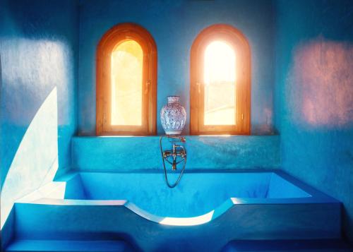 Baño azul con bañera y 2 ventanas en Riad Roxanne en Marrakech