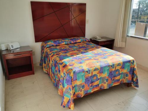 a bedroom with a bed with a colorful comforter at Hotel Villa Esmeralda in Cuautla Morelos