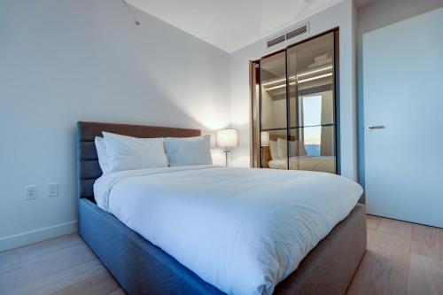 una camera da letto con un grande letto bianco e uno specchio di Downtown Properties a Vancouver