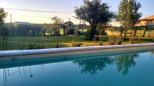 una piscina de agua con árboles y casas en el fondo en La Ernestina en Villa Giardino