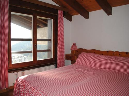 a bedroom with a bed with a red and white comforter at Residence Cransalpin in Crans-Montana