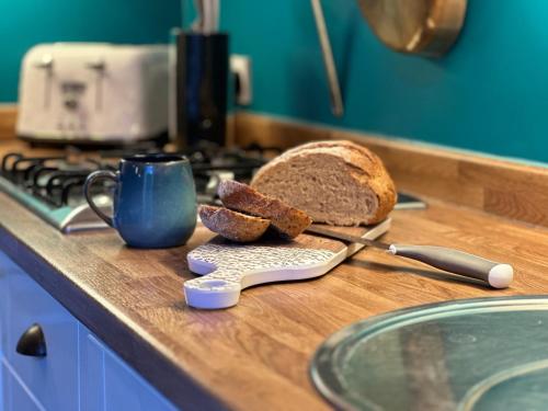 a counter with a loaf of bread and a coffee mug at Snowdrop Cottage in Bulmer