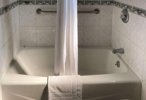 El baño incluye bañera blanca con cortina de ducha. en Motel 6 Glendale CA Pasadena Burbank Los Angeles, en Glendale