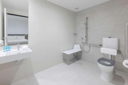 a white bathroom with a toilet and a sink at Best Western Queen Victoria Market Hotel in Melbourne