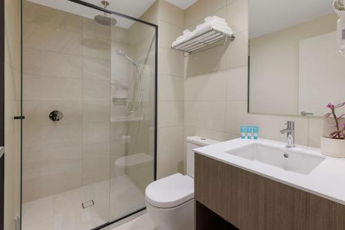 a bathroom with a shower and a toilet and a sink at Best Western Queen Victoria Market Hotel in Melbourne
