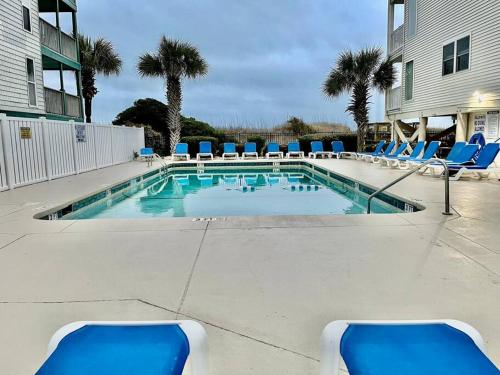 a swimming pool with blue lounge chairs and a swimming pool at Lovely 2 bedroom condo with ocean view 304 in Myrtle Beach
