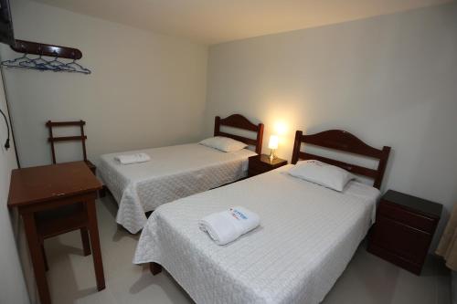 Habitación con 2 camas, mesa y lámpara. en Witobi Hostal, en Cajamarca