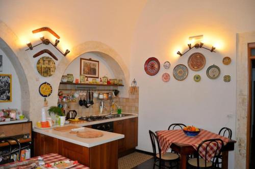een keuken met bogen en een tafel en stoelen bij Bed & Breakfast Hostel H24 in Ragusa