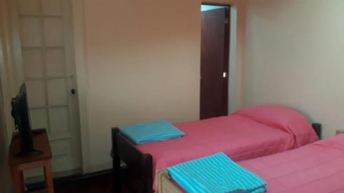 two beds in a room with pink and blue sheets at Hostería Residencial Santa Rosa in Los Andes
