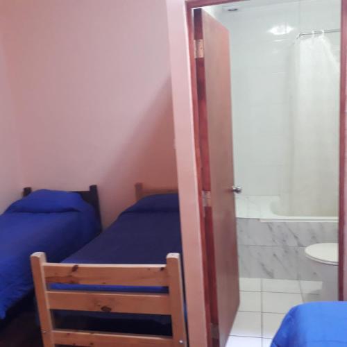 a bedroom with two beds and a bathroom with a shower at Hostería Residencial Santa Rosa in Los Andes