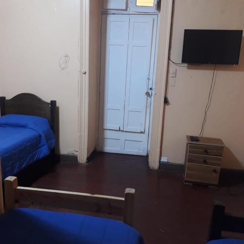 a room with a bed and a tv and a door at Hostería Residencial Santa Rosa in Los Andes