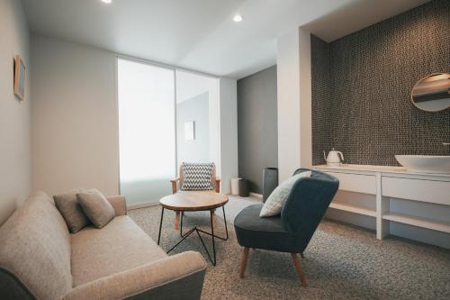 a living room with a couch and a chair at LAZULI Hiroshima Hotel and Lounge in Hiroshima