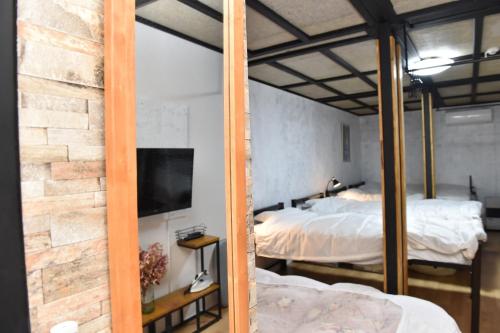 a bedroom with two beds and a tv and a brick wall at Motel inn Minami Otaru / Vacation STAY 50444 in Otaru