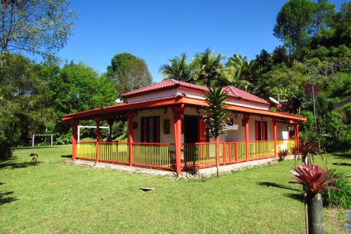 una pequeña casa roja y amarilla en un patio en CASA DE CAMPO VILLA OLI!! - Un paraiso natural en la ciudad, en Villamaría