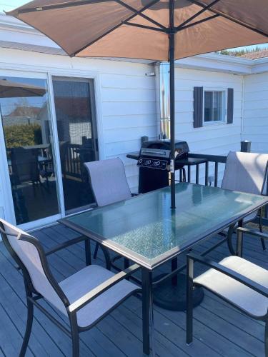 a table and chairs on a deck with an umbrella at Maison Carofanne in Saint-Siméon