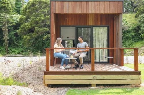 a man and woman sitting on a porch of a tiny house at Timboon Tiny Homes in Timboon