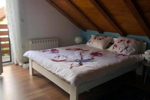 ein Schlafzimmer mit einem weißen Bett mit Blumen darauf in der Unterkunft Holiday house with a parking space Fuzine, Gorski kotar - 20332 in Fužine