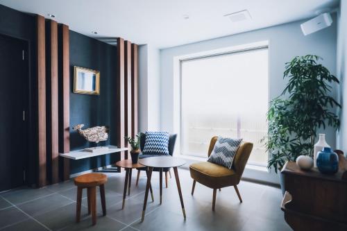 a living room with a table and chairs and a window at LAZULI Hiroshima Hotel and Lounge in Hiroshima