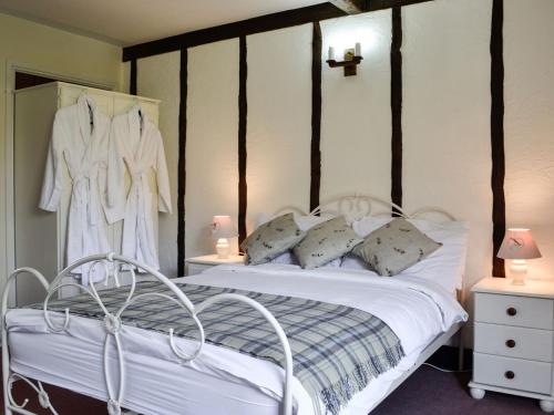 Cette chambre comprend un lit avec des draps blancs et une croix sur le mur. dans l'établissement Robins Retreat - Uk6548, à Llanfihangel-Bryn-Pabuan