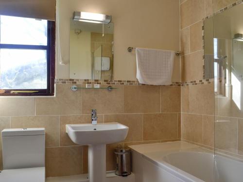 La salle de bains est pourvue d'un lavabo, de toilettes et d'une baignoire. dans l'établissement Robins Retreat - Uk6548, à Llanfihangel-Bryn-Pabuan