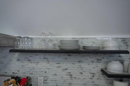 a shelf with plates and glasses and dishes on it at Modern, Luxury 2 Bedroom Apt in Prime Location in Schenectady