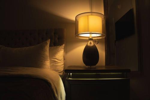 a lamp on a night stand next to a bed at Modern, Luxury 2 Bedroom Apt in Prime Location in Schenectady