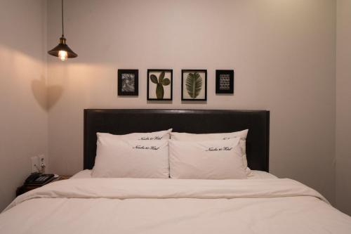 a bed with white pillows and pictures on the wall at No25 Hotel Yeonsan in Busan