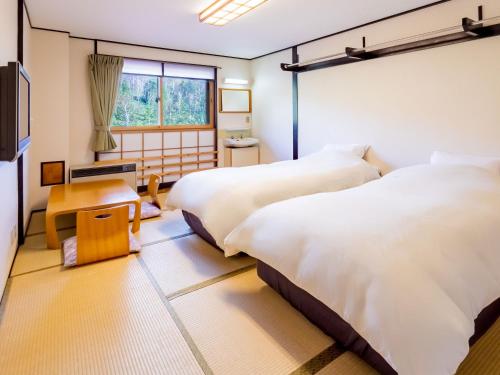 um quarto com 2 camas e uma janela em Sachinoyu Hotel Shiga Kogen em Yamanouchi
