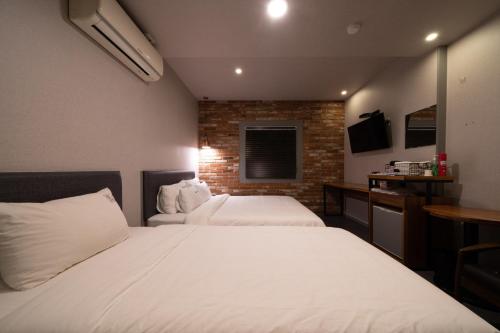 a bedroom with two beds and a brick wall at No25 Hotel Yeonsan in Busan