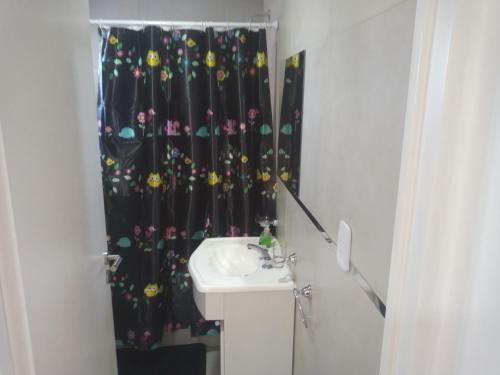 baño con lavabo y cortina de ducha negra en El Serrano 2 en Tandil