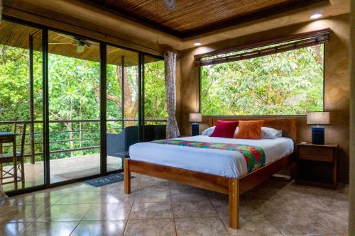 a bedroom with a bed and large glass windows at Arbol Verde Villas in Ojochal