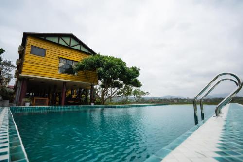 a house with a swimming pool next to a building at Greenfield Ecostay in Phong Nha