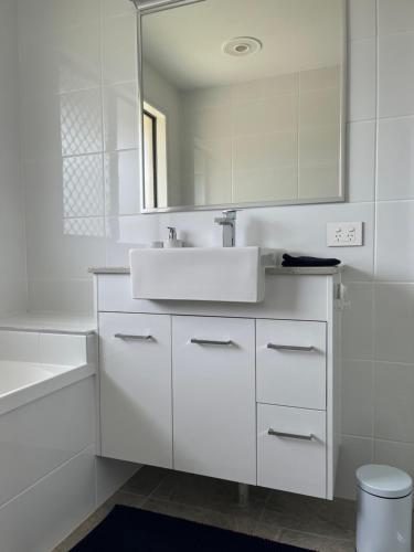 Baño blanco con lavabo y espejo en Freyjas Guest Suite en Curra