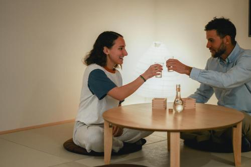 un hombre y una mujer sentados alrededor de una mesa bebiendo vino en NAGI Hiroshima Hotel and Lounge en Hiroshima
