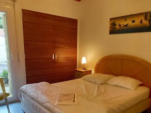 une chambre avec un lit avec une tête de lit en bois dans l'établissement Charmant pavillon à Saint-Jean-de-Monts: 2 chambres, proche plage, forêt et commerces, jardin clos - FR-1-323-259, à Saint-Jean-de-Monts