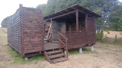 a wooden out house with a wooden staircase in a field at PARCELA DE AGRADO CON PISCINA LAGO RANCO todas las instalaciones con uso exclusivo capacidad 20 personas in Lago Ranco
