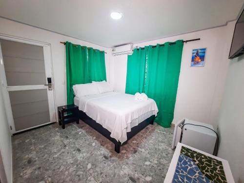 a bedroom with green curtains and a white bed at Hotel Posada Enilda in Providencia