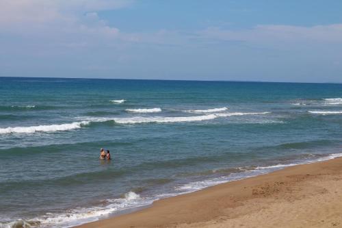 two people standing in the water at the beach at Nikos 5 in Kakóvatos