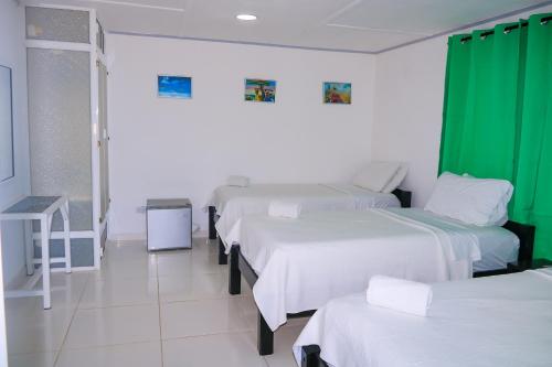 a room with four beds and a green curtain at Hotel Posada Enilda in Providencia