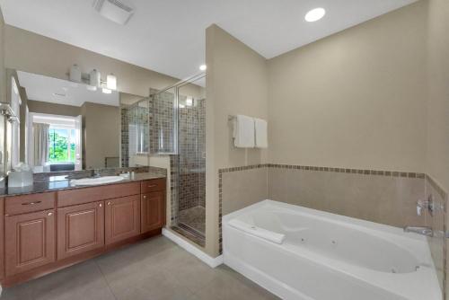 a bathroom with a tub and a shower and a sink at The Point, Lux Apartment 4 min from Universal in Orlando