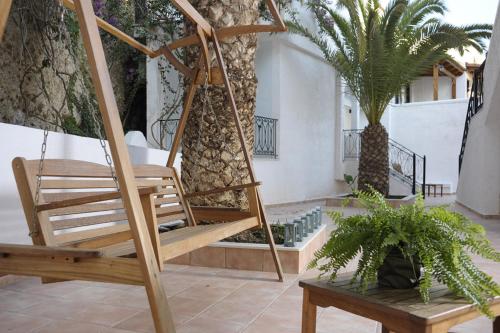 a porch with a swinging chair and palm trees at Glaros Hotel Apartment in Agia Galini