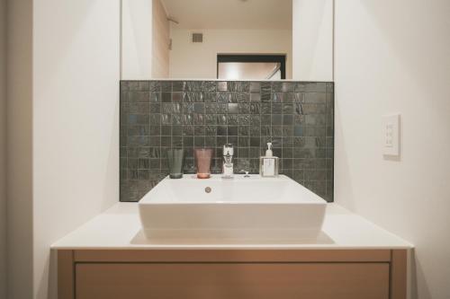 uma casa de banho com um lavatório branco e um espelho. em NAGI Hiroshima Hotel and Lounge em Hiroshima