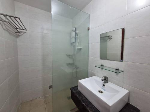 ein weißes Bad mit einem Waschbecken und einer Dusche in der Unterkunft Cozy studio 5 min walk from Ayala, Cebu Business Park in Cebu City