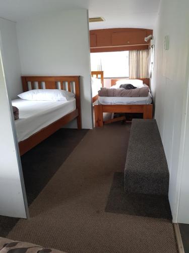 a small room with two beds and a window at Te Puru Holiday Park in Thames