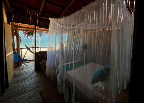 1 dormitorio con cama con dosel y vistas al océano en Palmarío Hostal en Guachaca