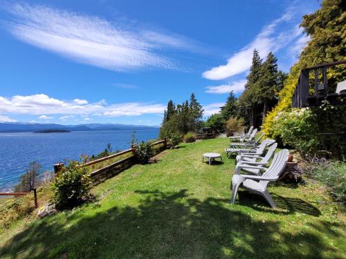 a row of white benches sitting next to the water at Destinar Apartments in San Carlos de Bariloche
