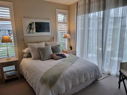 a bedroom with a large bed and a large window at Omokoroa Golfers Retreat - B&B in Omokoroa