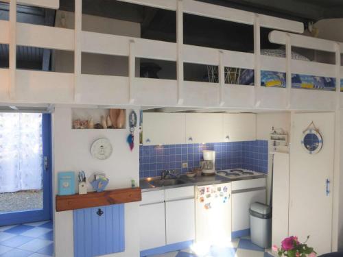 Il comprend une cuisine avec des placards blancs et un mur carrelé bleu. dans l'établissement Charmante Maison avec Piscine Chauffée et Tennis, Proche Plage, Bretignolles-sur-Mer - FR-1-224A-59, à Bretignolles-sur-Mer